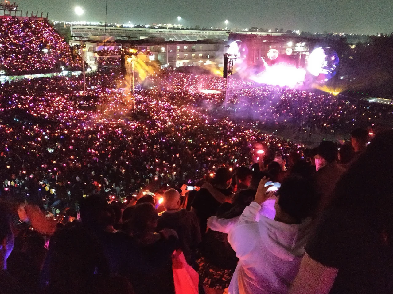 A Coldplay stadium show at night, sea of glowing wristbands