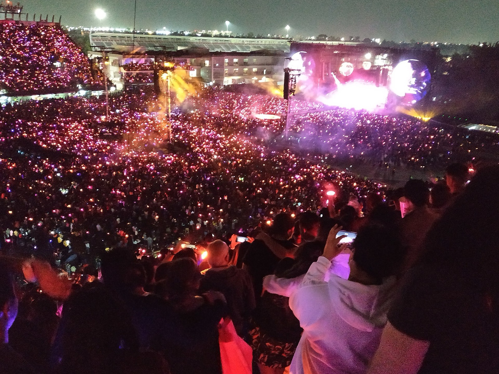 A Coldplay stadium show at night, sea of glowing wristbands