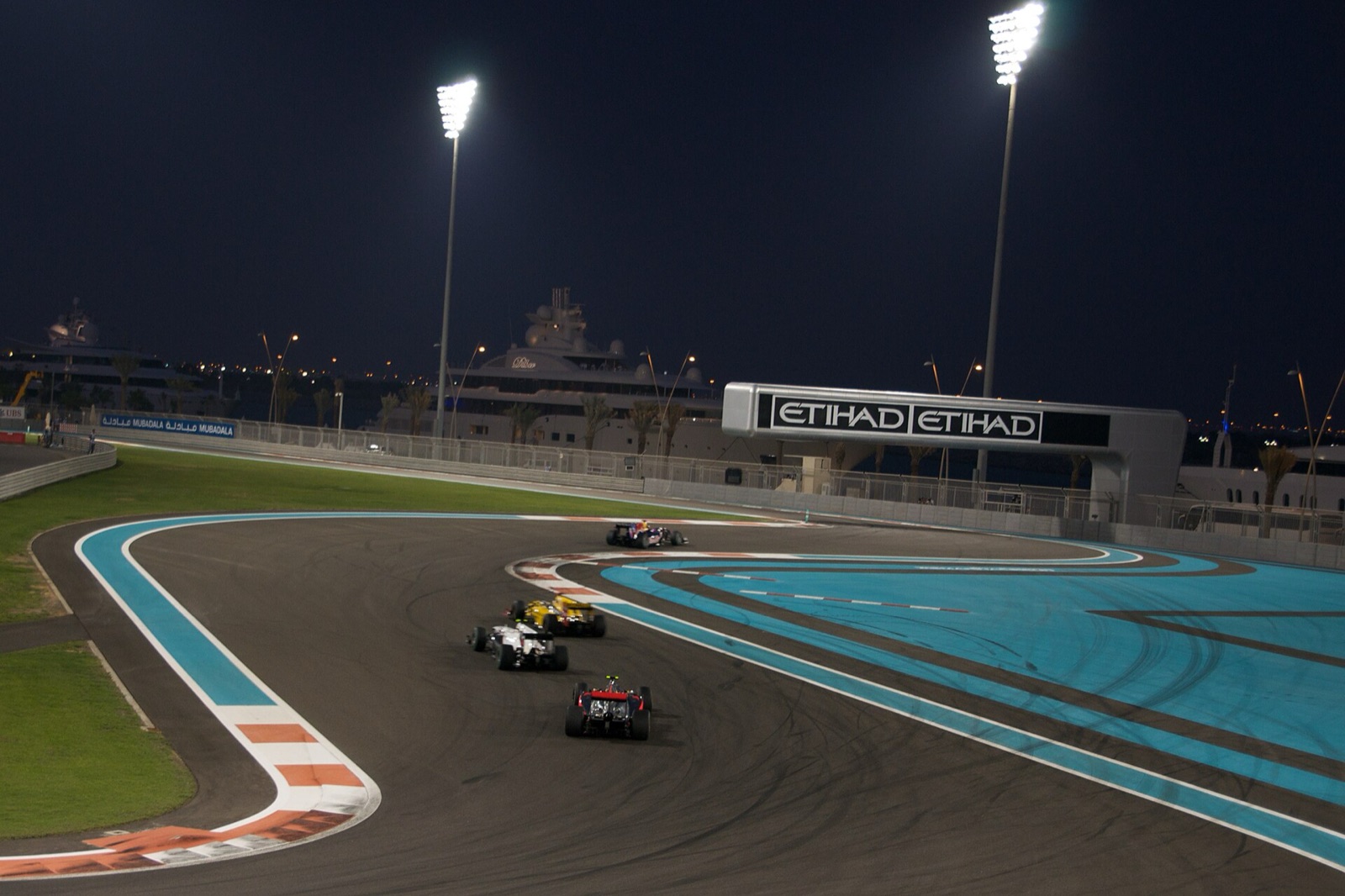 Formula 1 cars racing under floodlights at Yas Marina
